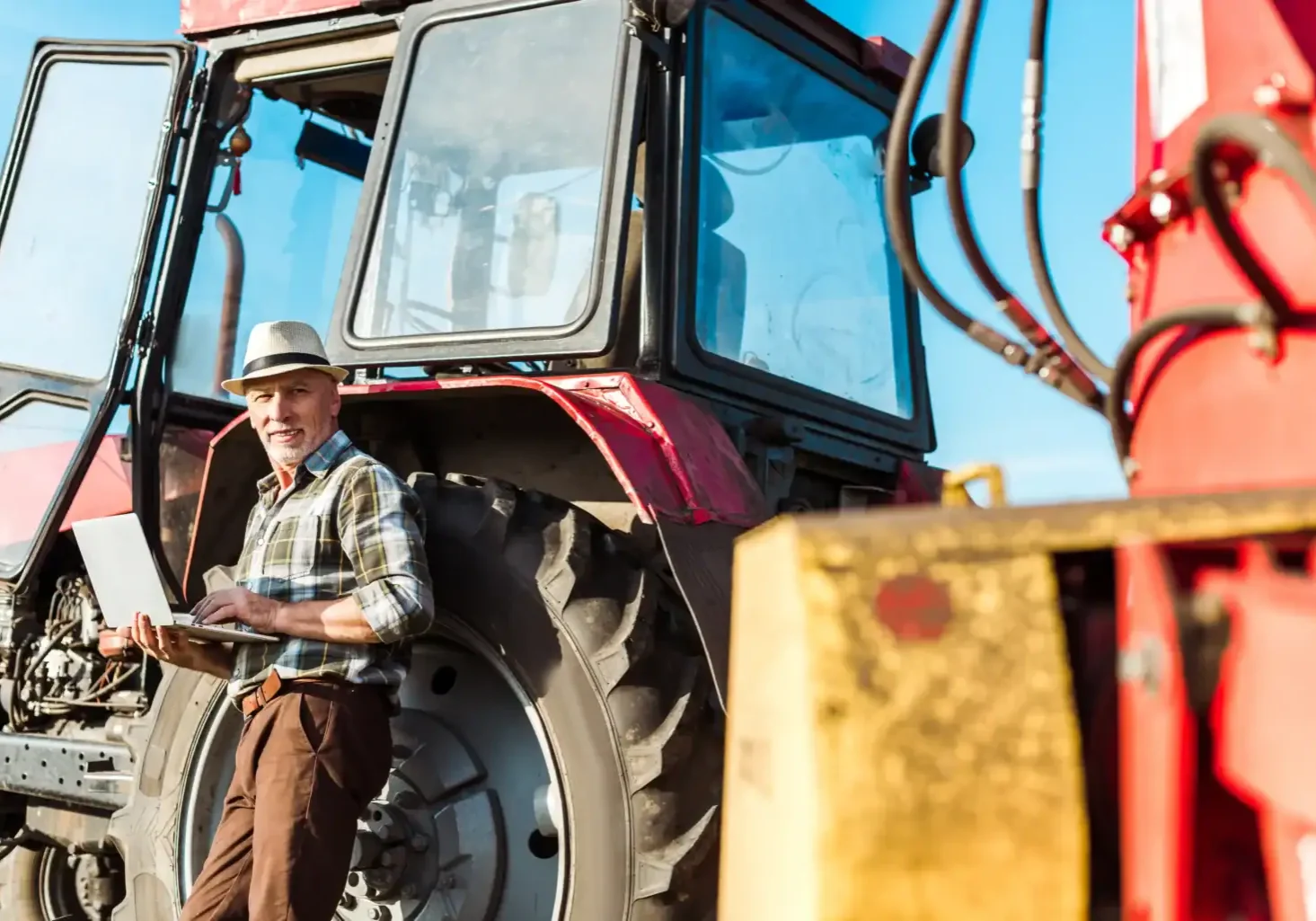 man-with-laptop-standing-by-red-tractor-outdoors-2026-01-06-00-42-40-utc